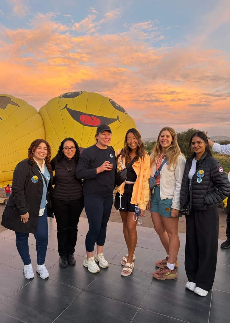Teammates in front of hot air balloons at sunrise