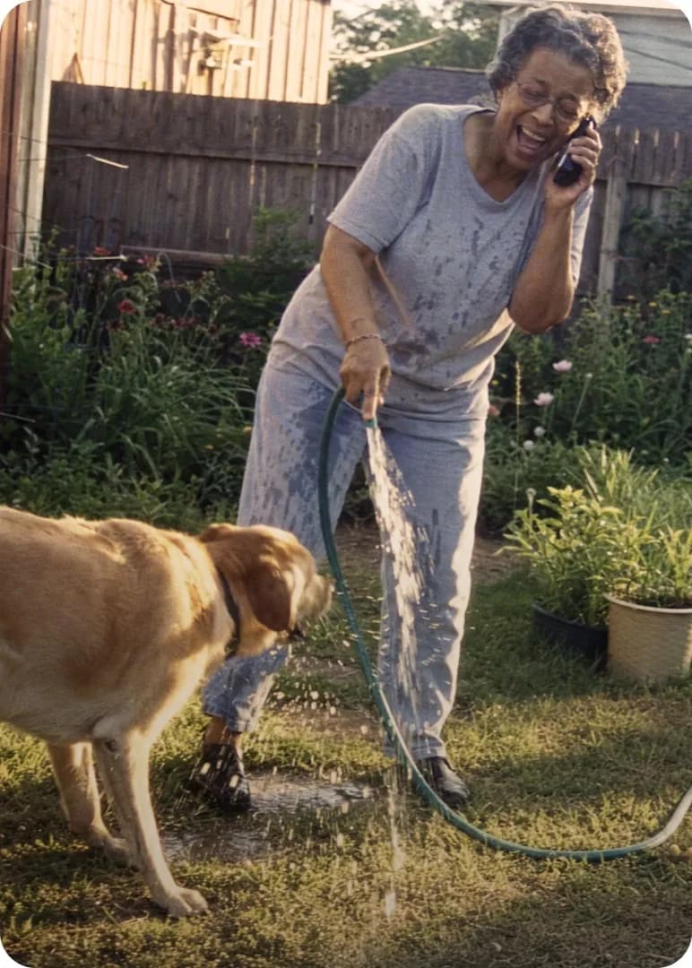 Customer smiling on the phone while gardening with her dog
