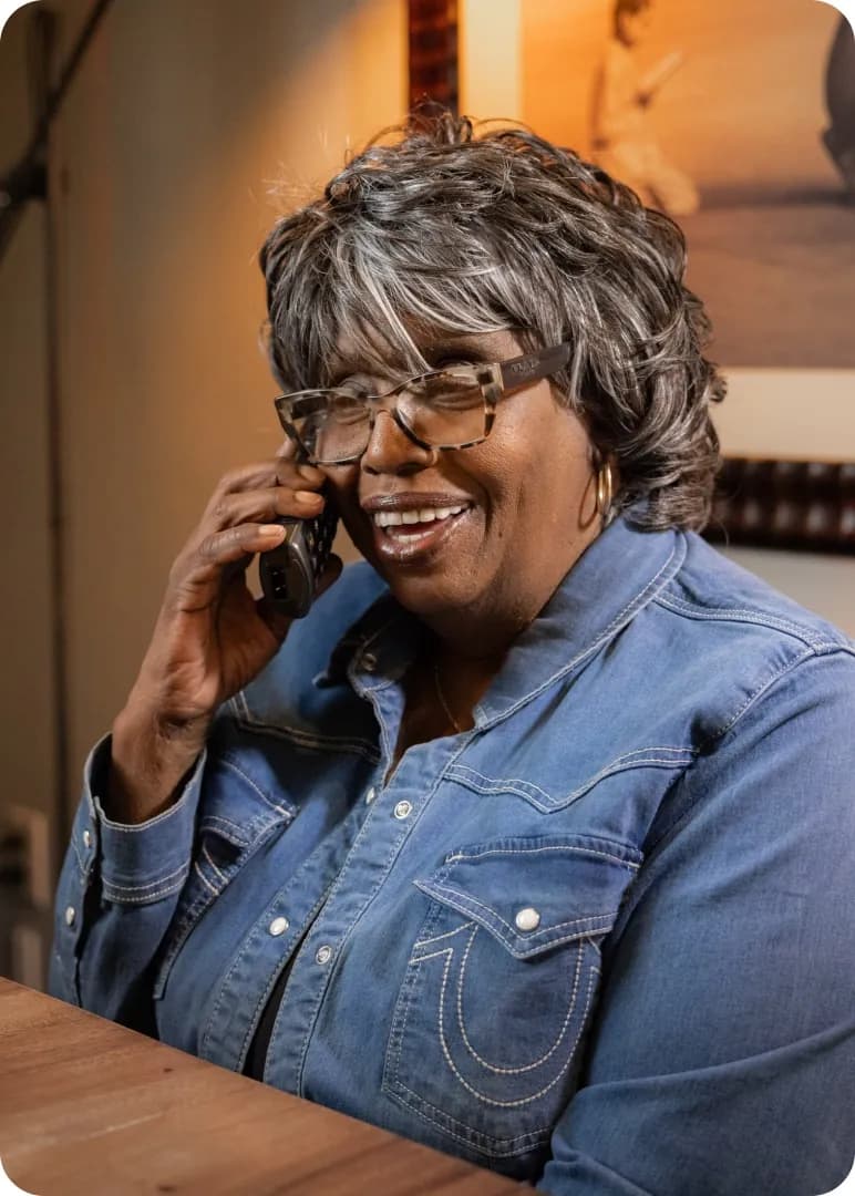 Customer smiling while talking on the phone at her kitchen table