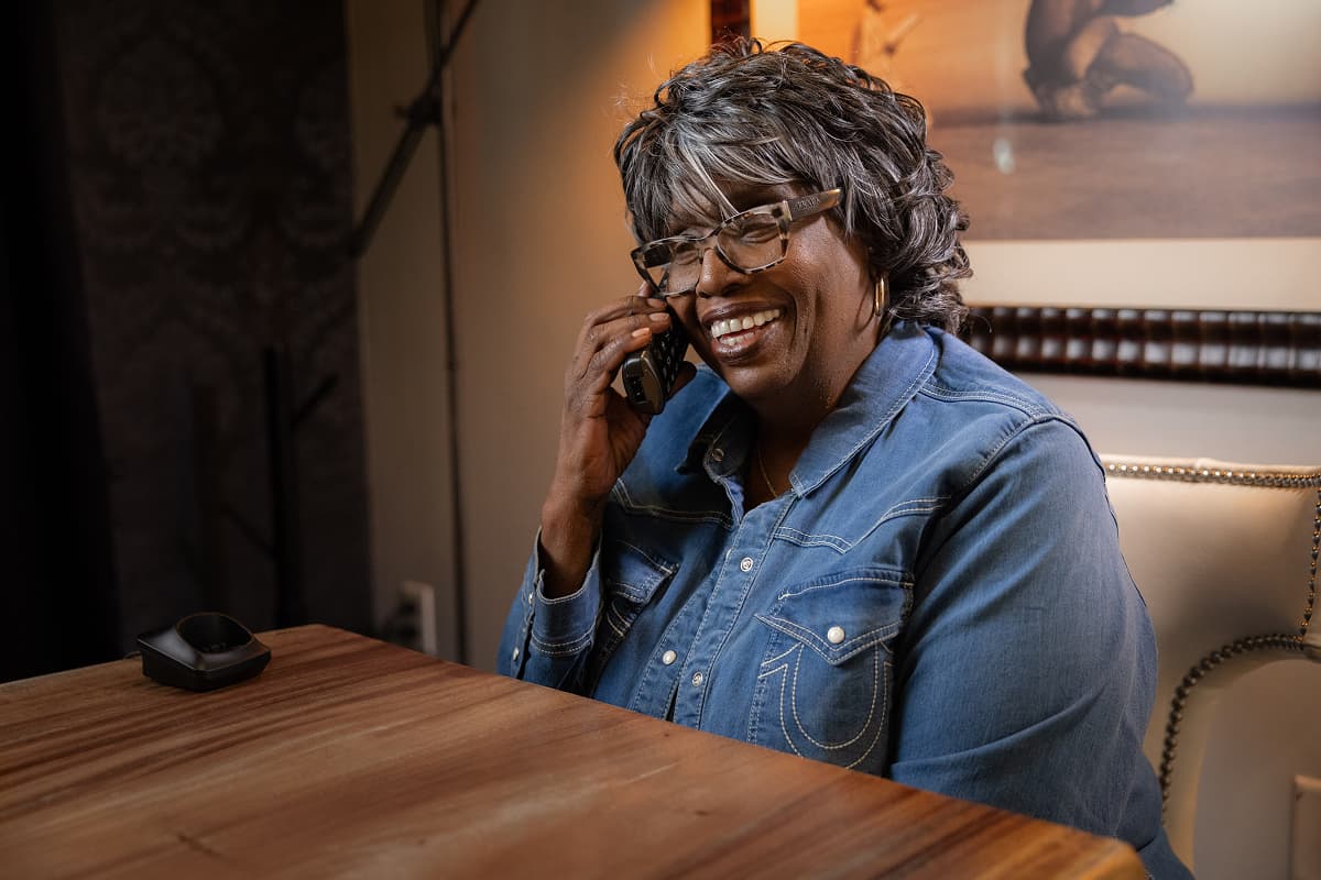 A woman laughing on her home phone, mid-conversation with someone she loves.