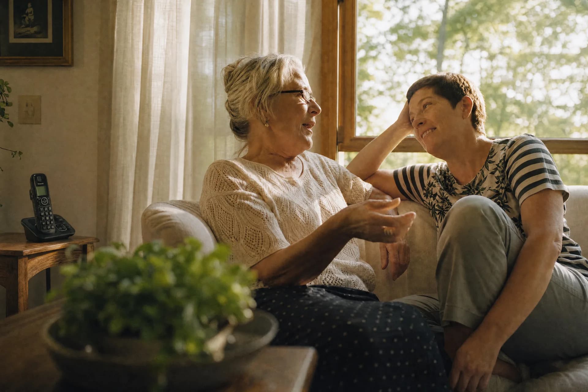 Two people talking in a living room with a cordless home phone nearby